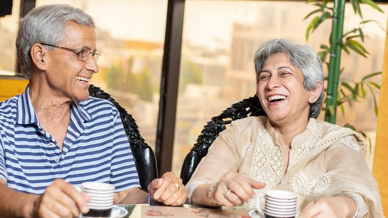 An elderly couple at home together over coffee